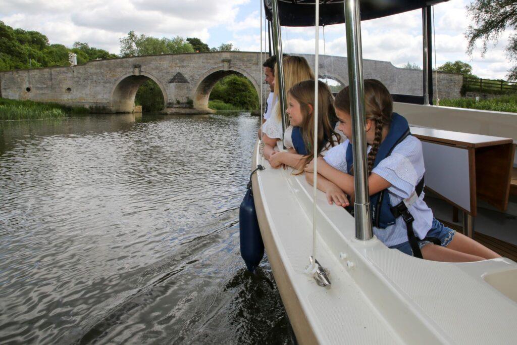 A group of four are taking a boat trip along a river.