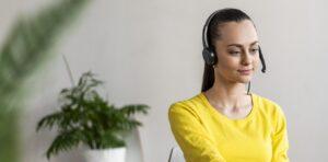 A woman dressed in a bright yellow shirt is also wearing a headset and mic