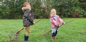 Two children playing with the broomsticks they have made