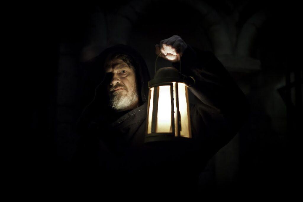 A mysterious cloaked figure carrying a lantern