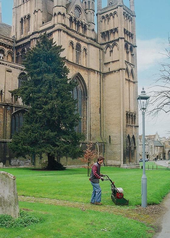 Young man mowing grass outside cathedral
